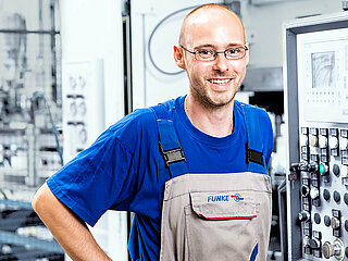 FUNKE employee in front of the machine control unit of a machine in the production of heat exchangers