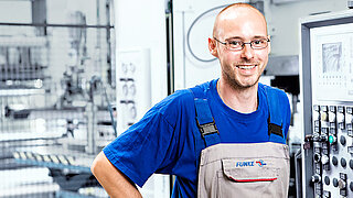 Employé de FUNKE devant l'unité de commande d'une machine dans la production d'échangeurs de chaleur