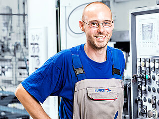FUNKE employee in front of the machine control unit of a machine in the production of heat exchangers